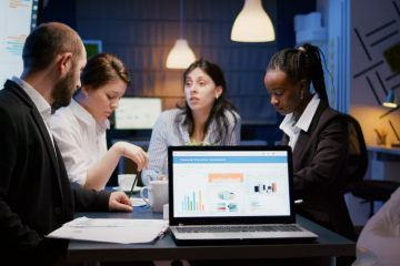 Team of professionals discussing lead management software strategies in a modern office with laptops and data charts.